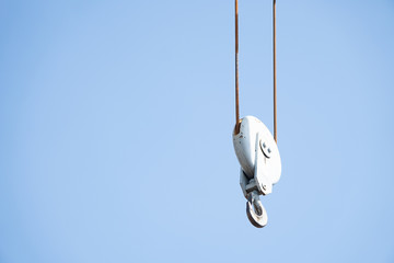 a crane hook haging over blue sky at port