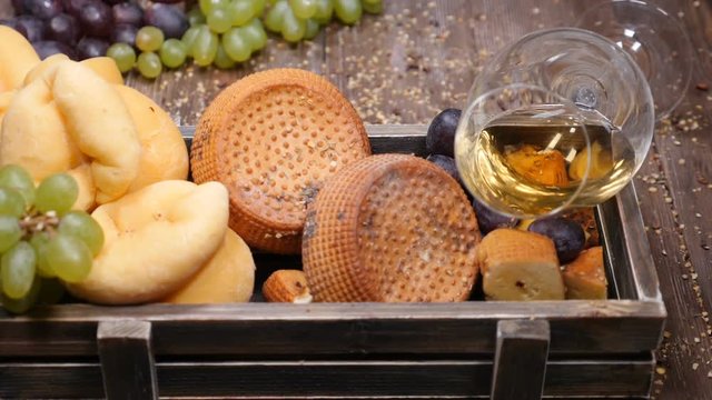 Closeup shot of red wine in glass and set of fresh delicious cheese placed in wooden box. Wine and cheese concept. Luxury restaurant concept. Food art. hd