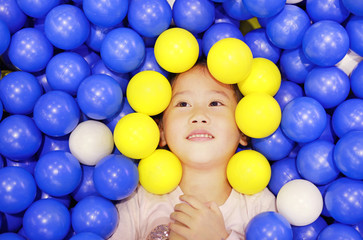 Fototapeta na wymiar Adorable Asian cute girl playing with color plastic balls.