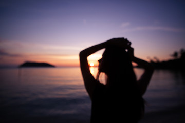Blurred abstract background. Silhouette of a beautiful slim young woman on a background of bright colorful sunset on a tropical beach