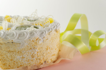 cake on a pink and white background with a green ribbon shot from the side