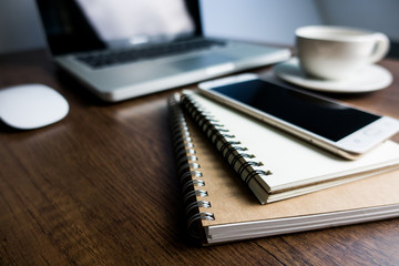 Close up office desk table with laptop, note book, mobile coffee and pen. Selective focus. Business concept. Copy space.