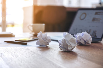 Closeup image of laptop, mobile phone and screwed up papers on wooden table in office