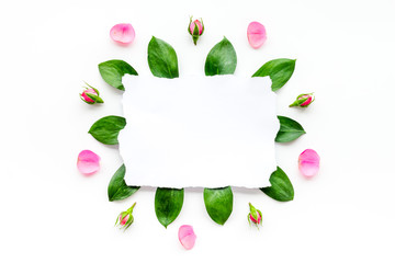 Template for greeting card. Mockup with flowers, petals, leaves, white paper on white background top view frame