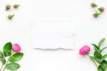 Template for greeting card. Mockup with flowers, petals, leaves, white paper on white background top view frame