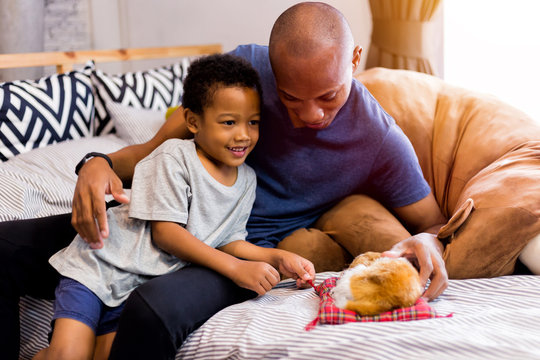 African American family of two playing with a dog pet in bedroom