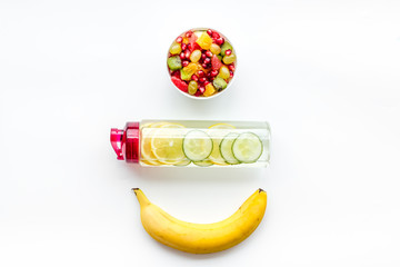 Weight loss concept. Fruit salad near fruit lemon and cucumber water on white background top view copy space