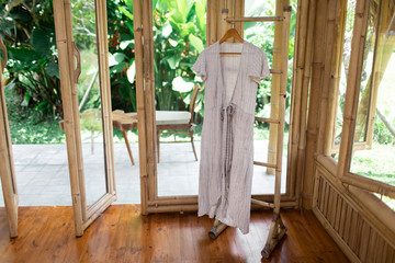 Grey Linen dress is hanging on hangman in a bamboo house room. Summer natural dress. Eco concept.
