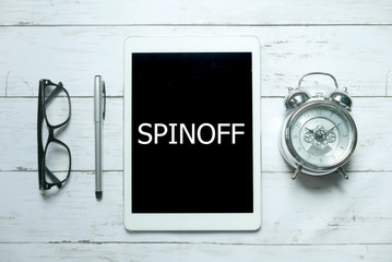 Business concept.Top view of glasses,clock,pen and tablet written with Spinoff on white wooden...