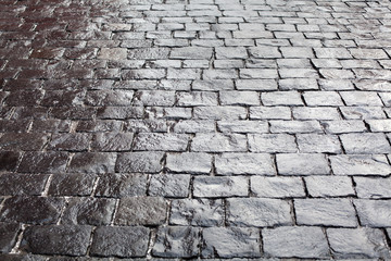 Cobblestones on pavement background, stone sidewalk texture gray or black color, wet bricks road surface pattern top view closeup