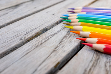 Colorful rainbow color pencils on wooden plank