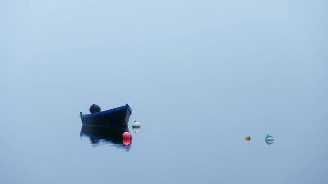Nice little blue fishing boat at anchor in a quiet foggy cove with no horizon line visible. Great background for graphics or title page. Isolated.