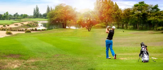 Gordijnen Panorama of Golfer hit sweeping golf ball on blurred  beautiful golf course with sunshine on background. © Nischaporn