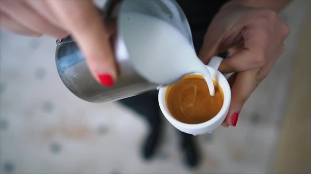 Hand of barista making latte or cappuccino coffee pouring milk making latte art