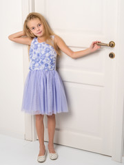 A little girl is standing by the door.