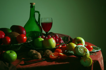 Wine and fruits. A glass of wine and a bottle surrounded by fruits on a table with a brown...