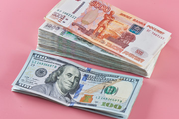 Rubles and dollars. Russian and American paper money on a pink background