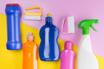 on a yellow pink background, a set of items for cleaning, multi-colored bottles with liquids for cleaning the house and brushes