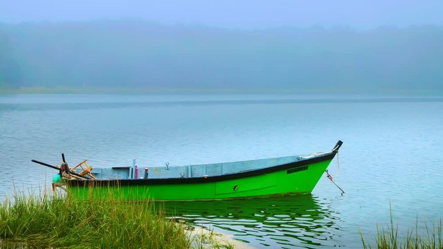Cute little green rowboat dinghy moored in a foggy marshland on Cape Cod
