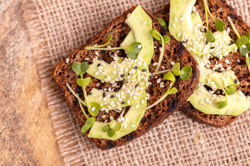Healthy rye toasts with avocado, radish sprouts and sesame