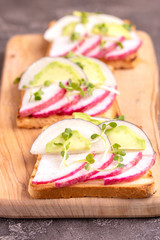 Tasty wheat toasts with radish, avocado and sprouts