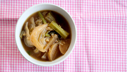 Chinese vegetable soup in white bowl on pink background and space for write wording, traditional low cost Chinese food from many kinds of vegetable and pork, served in Thai or Chinese restaurant