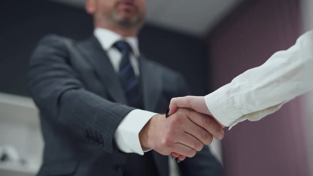 Hiring, man in a suit, a businessman shaking hands with a woman colleague, a handshake in the office.