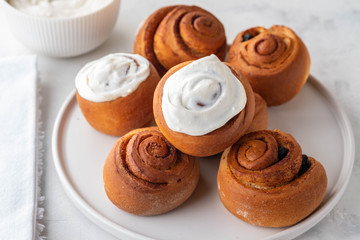Delicious Cinnamon Rolls with cheese cream on a white plate. Copy space.
