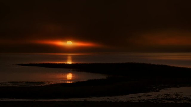 Ocean sunset with marshlands and foggy low cloud cover