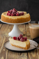 Piece of classic cheesecake with raspberries and coffee on a wooden background. Copy space.