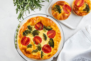 Vegetable pie quiche with broccoli, tomatoes and soft cheese on white background.