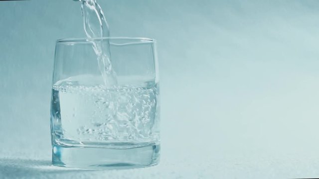 Water pour into a glass on a white background