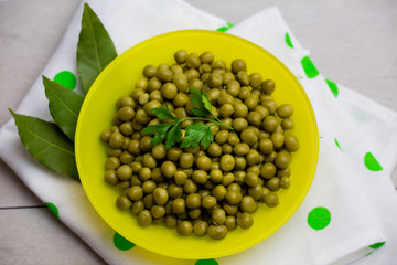 green peas decorated with a sprig of parsley in a yellow plate close-up