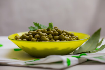green peas decorated with a sprig of parsley in a yellow plate close-up