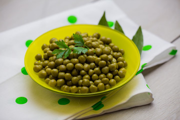 green peas decorated with a sprig of parsley in a yellow plate close-up