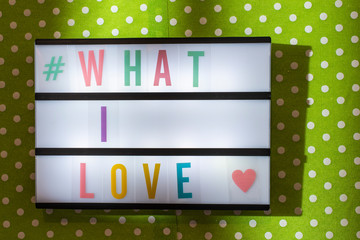 Message What I Love on illuminated board. Love affirmation concept with text. Daylight from window.