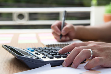 Fototapeta premium businessman hand using calculator Calculating bonus(Or other compensation) to employees to increase productivity.Writing paper on desk.Selective Focus