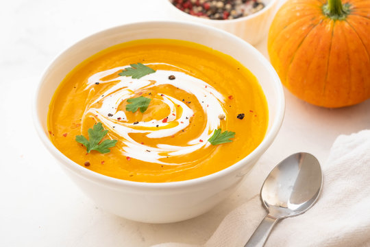 Pumpkin soup with cream and pumpkin seeds isolated on white background. Autumn concept.
