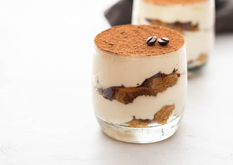 Classic tiramisu in a glass on a white background. Copy space.