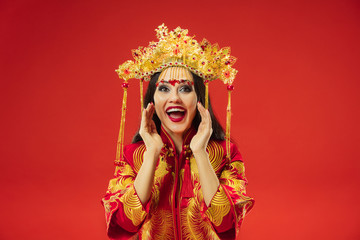 Chinese traditional graceful woman at studio over red background. Beautiful girl wearing national costume. Chinese New Year, elegance, grace, performer, performance, dance, actress, emotions concept