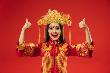 Chinese traditional graceful woman at studio over red background. Beautiful girl wearing national costume. Chinese New Year, elegance, grace, performer, performance, dance, actress, emotions concept