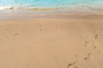 Fototapeta na wymiar Footsteps on the beach sand at the sea shore