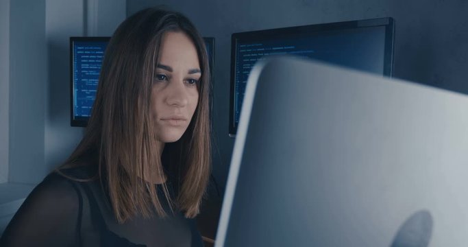 Young Woman Developer Programmer looking at camera at binary code background