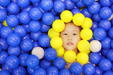 Fototapeta na wymiar Adorable Asian cute girl playing with color plastic balls.