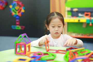 Fototapeta na wymiar Little child girl playing Magnets toy for brain development.