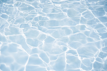 Blue water surface with bright sun light reflections, water in swimming pool background