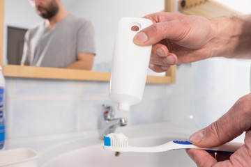 Person putting toothpaste on toothbrush