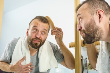 Obraz premium Man using comb in bathroom