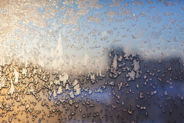 Fototapeta na wymiar Frosty snowflake pattern on the window glass and city lights
