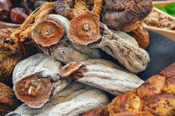 Dried persimmon, figs and melon on a black plate on the wooden background. Close-up. Background